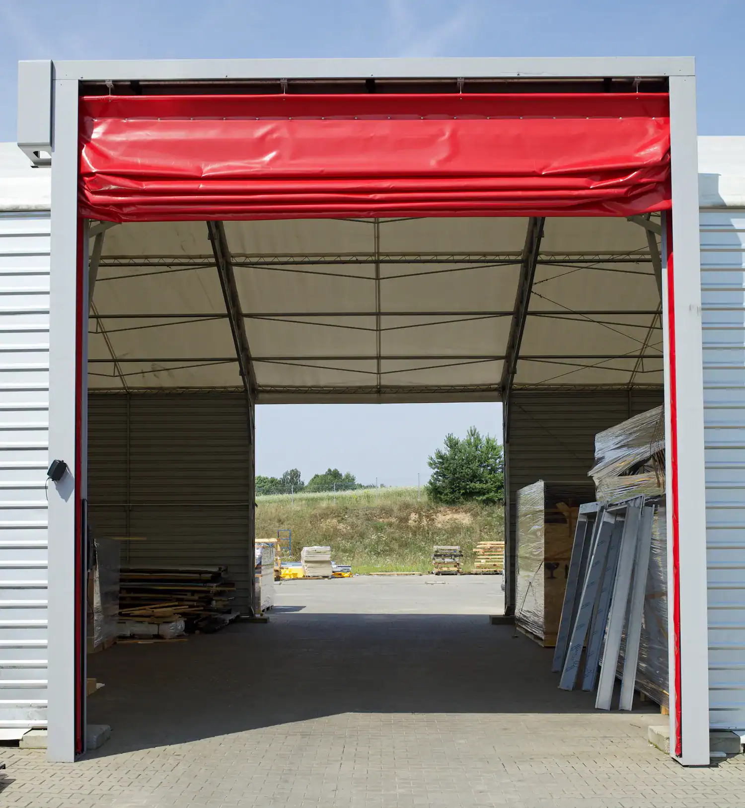 Puertas plegables industriales completamente plegadas junto al marco.