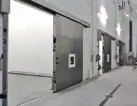 Portón corredizo industrial abierto para permitir el paso de vehículos en áreas de carga de una planta alimentaria.