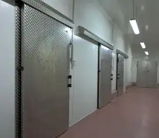 Pasillo industrial con tres puertas de acero corredizas en perfecto estado gracias al mantenimiento de puertas industriales especializado para bodegas y centros logísticos